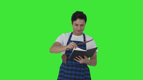 Happy Indian cook making food from recipe book Green screen