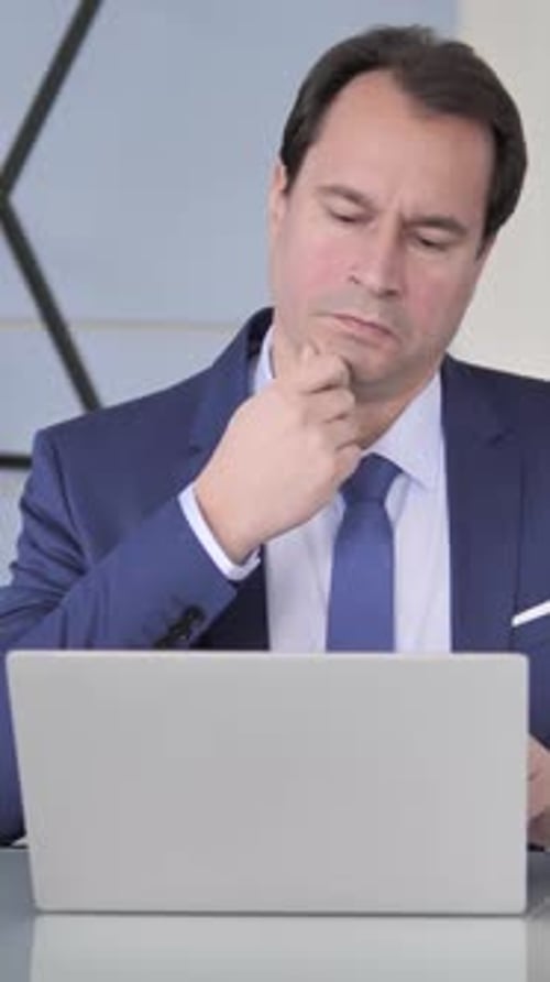 Thoughtful Businessman Working on Laptop in Office