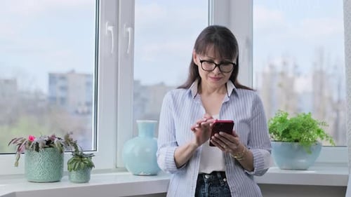 Woman Using Smartphone by Sunny Window