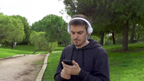 Man Listens to Music and Uses Phone in Park