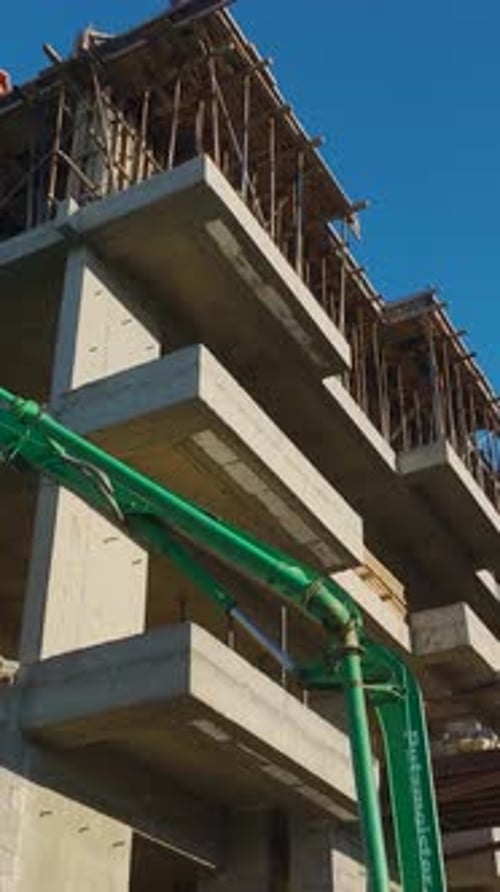 Vídeo vertical de ingenieros supervisando la construcción mientras los trabajadores construyen paredes y vierten hormigón