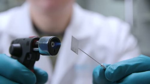 Employee Heats Small Metal Plate with Gas Burner in Shop