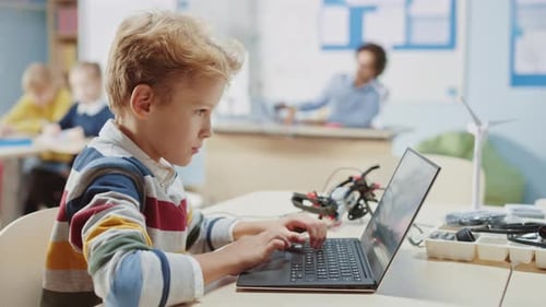 Young Schoolboy Uses Laptop to Program Software for Robotics Engineering Class. Elementary School S