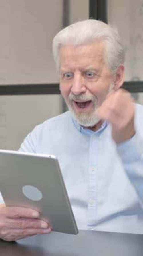 Senior Businessman Celebrating Success on Tablet in Office
