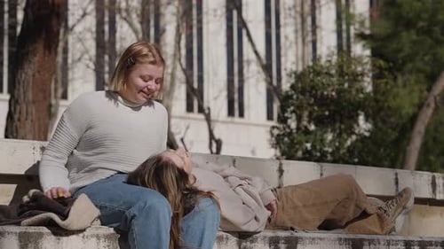 Friends Relaxing Together on Concrete Bench in Park