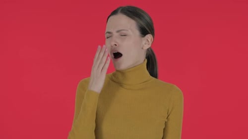 Jeune femme décontractée bâillante sur fond rouge, portrait