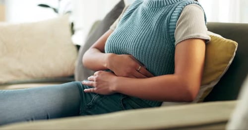 Mujer, dolor de estómago y calambres en el hogar durante la menstruación, la digestión o la inflamación