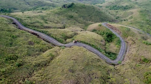Luftaufnahme der kurvigen Bergstraße mit Bagger in üppigen Hügeln