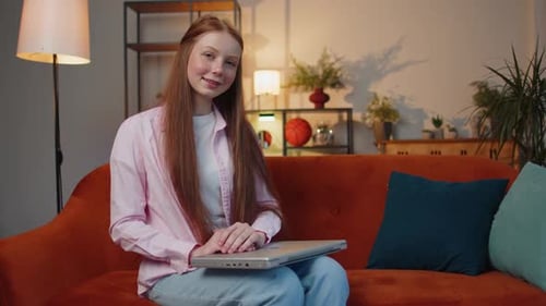 Teenager-Mädchen sitzt auf dem Sofa und schließt nach Abschluss der Arbeit im heimischen Wohnzimmer den Laptop-PC