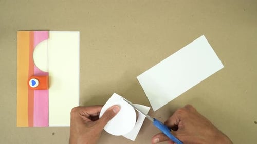 Cutting circle out of paper with scissors, crafting project, overhead view