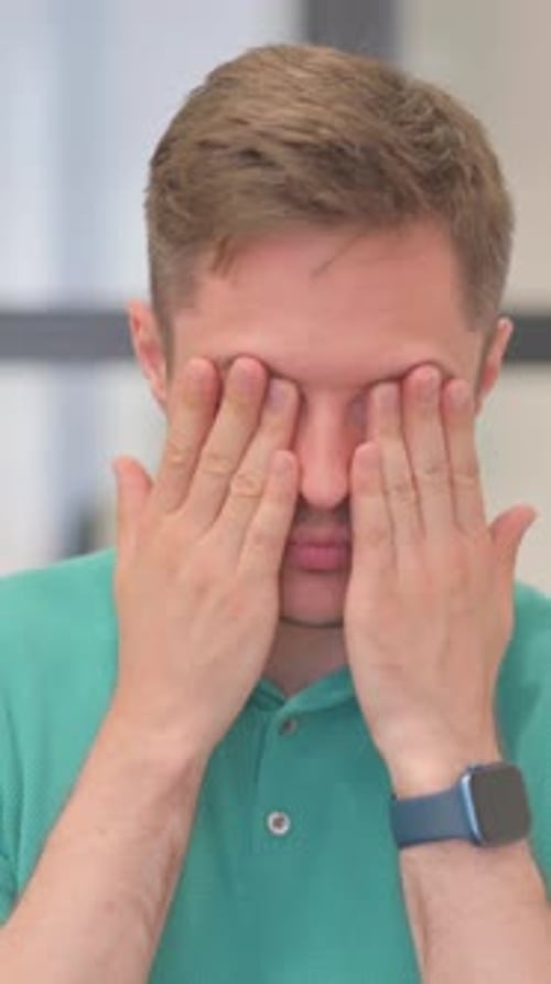 Man with headache rubs temples in distress