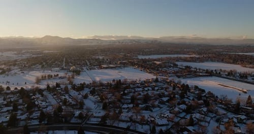 Drone shot of the sun setting over the Rocky Mountains in Denver, CO on a snowy winter day.