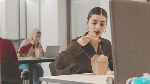 Woman Eats Takeout Noodles at Office Desk