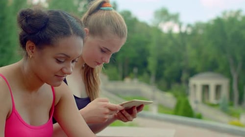 Girls Using Tablet in Park. Students Networking on Tablet in Park. Friends