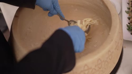 Chef Mixing Pasta Inside of a Cheese Wheel