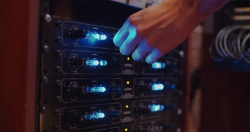 Hand of a man changing the gain of a Petrungaro preamplifier / Professional recording studio / at