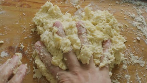 Hands Kneading Dough on Wooden Surface