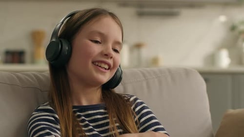 Smiling Girl with Headphones Listening to Music Indoors