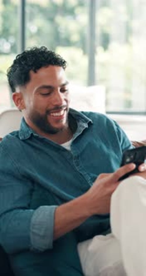 Happy Man Relaxing on Couch with Mobile Phone