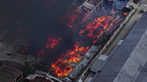 Inferno mit glühenden Flammen verwüstet Fabriklager im Industriegebiet, Luftaufnahme