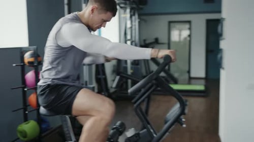 Athlete Man Has Cardio Workout While Cycling Stationary Bike in Gym