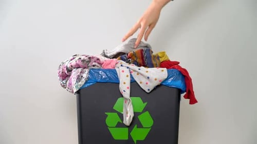 Clothes Being Thrown Into Recycling Trash Can