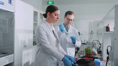Close Up Two Scientists with Protective Gloves Woman Holding Tubes in a Light Laboratory Medicine