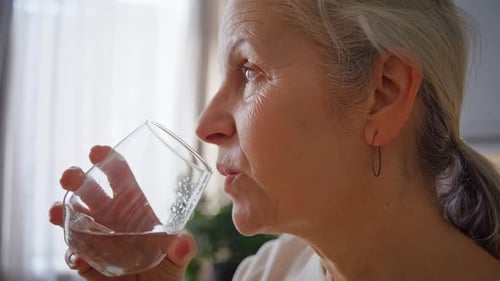 Senior Woman Taking Pill with Glass of Water