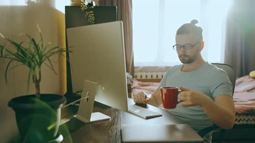 Man Working At Computer With Coffee In Bright Home