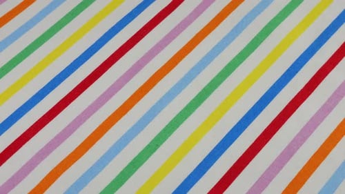 Top view of white cotton fabric with rainbow stripes rotated on the display case. Textile background