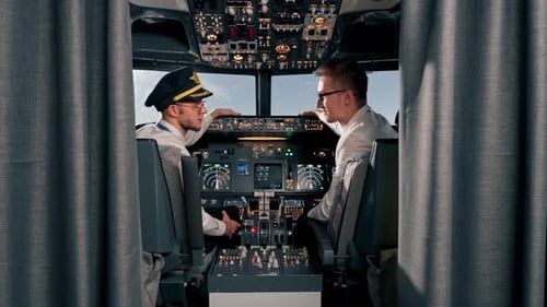 Portrait of smiling young captains of airplane pilots in uniform preparing for flight in simulator