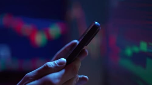 Hand Holding Phone with Data Chart Background