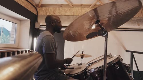 Lateral Medium Shot Of African American Musician Playing Drums Indoors