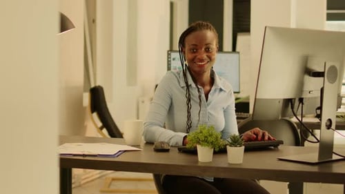Woman Typing in an Office Smiling