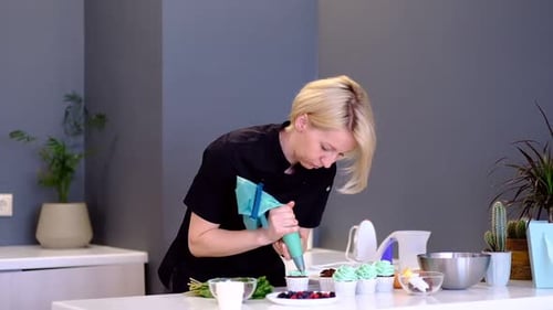 Woman Decorating Cupcakes with Frosting in Kitchen