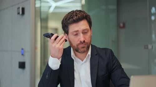 Professional Listens to Voice Message on Smartphone in Office