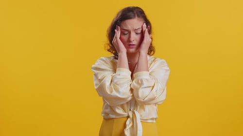 Woman with Headache Puts Hand to Head in Studio