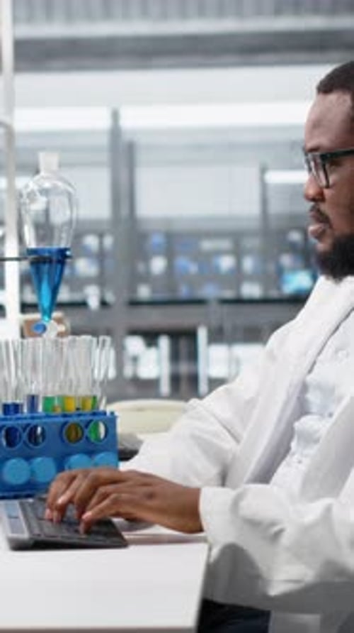Man in Lab Coat Typing at Desk
