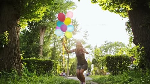 Woman Jumps with Balloons in Sunny Park