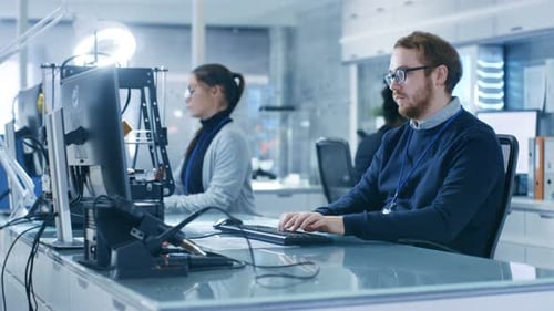 Young Bright Male Scienstists Works with His Colleagues on a Computer in a New Research Center.