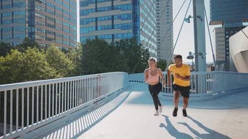 Fit Couple Runs Together on City Bridge