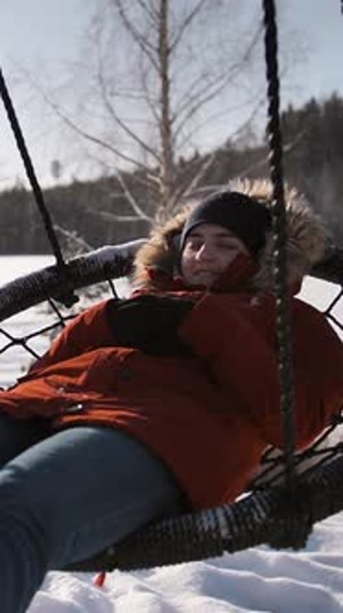 Woman Relaxing on Swing in Winter Landscape