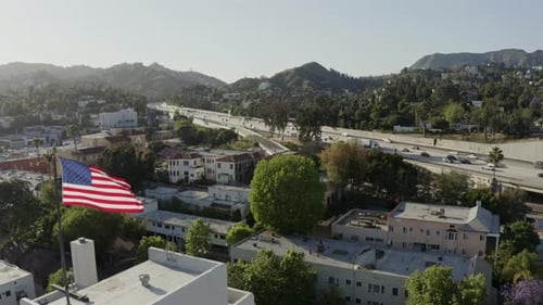 American Flag Waving Above City Near Highway