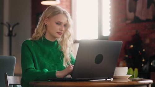 Freelancerin mit Laptop im Café mit modernem Loft-Interieur arbeitet aus der Ferne