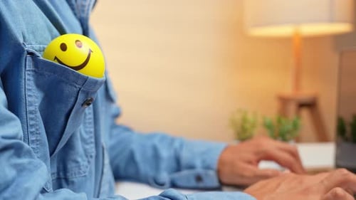 Der Smiley-Gesichtsball in einer Tasche bei der Arbeit am Laptop.