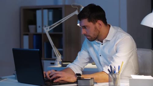 Business, Deadline And People Concept - Businessman With Laptop Computer Working At Night Office