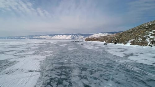 Aerial View on Tourist Cars Driving on Cracked Ice of Baikal to the Famous Tourist Spot Winter