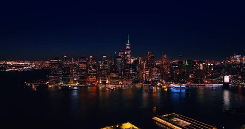 Luminous Manhattan in New York at night. Drone distancing from the waterfront of the East River.