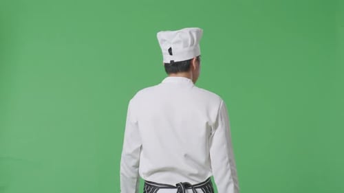 Back View Of Asian Man Chef Walking And Looking Around In The Green Screen Background Studio