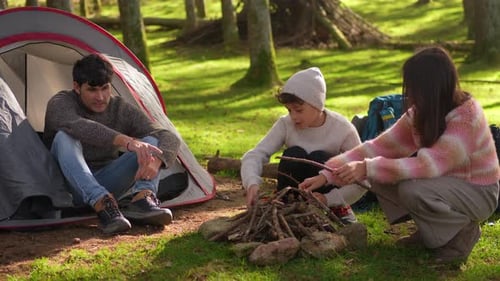 Family preparing open fire on camping trip